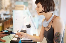 latina woman using a credit card to pay at a store