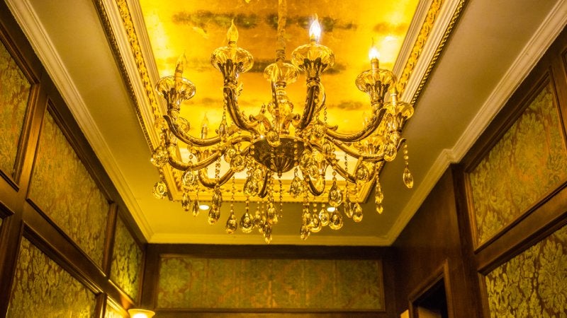 Tray ceiling featuring a lit chandelier 