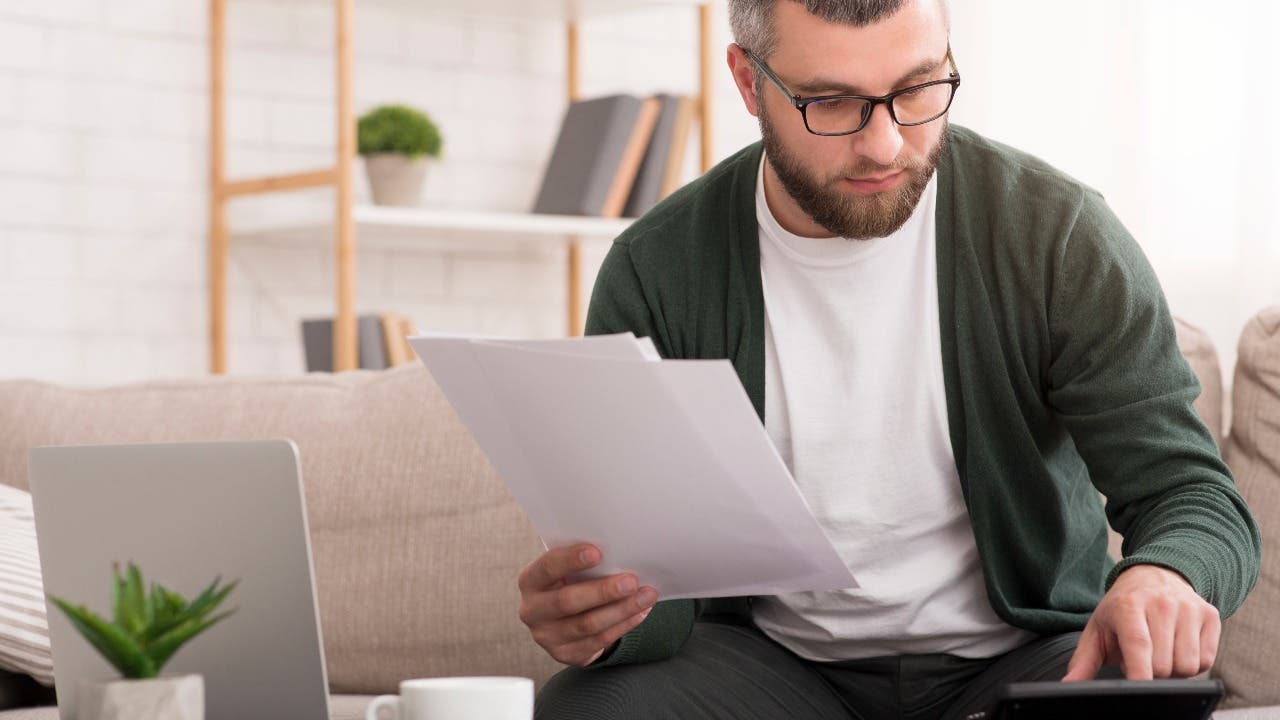 Man looks through paperwork with a calculator