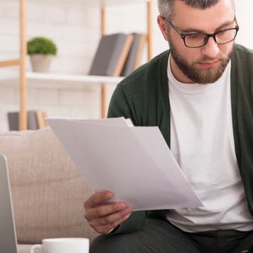 Man looks through paperwork with a calculator
