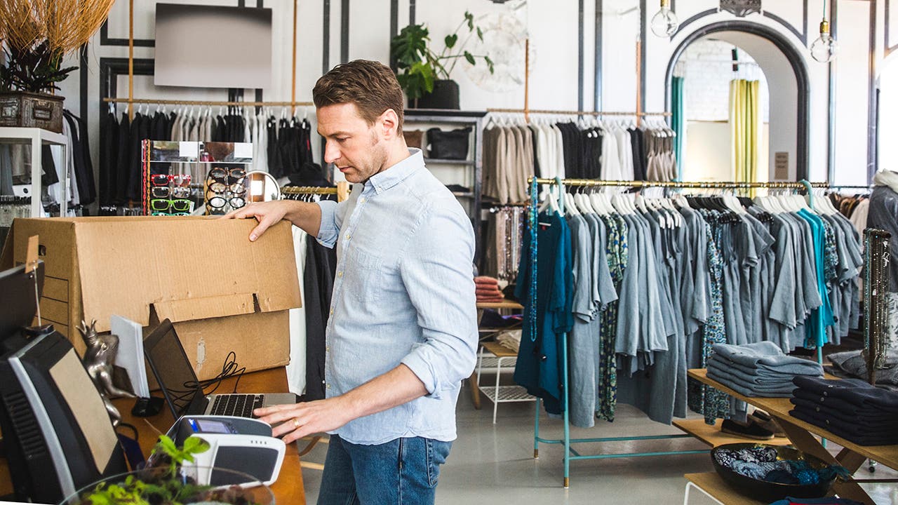 male business owner unpacking boxes in clothing boutique