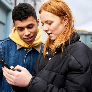 two teenage friends looking at a smartphone