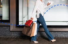 woman walking in a business district with multiple paper shopping bags