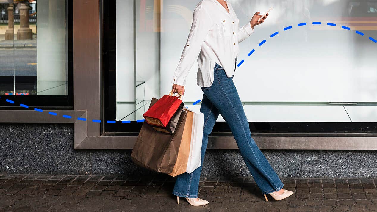 woman walking in a business district with multiple paper shopping bags