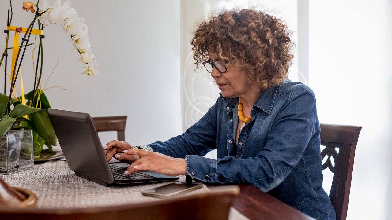 woman sitting at table and working on laptop computer