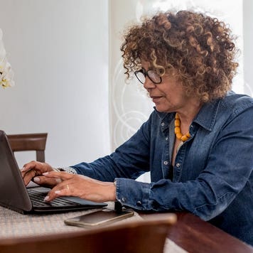 woman sitting at table and working on laptop computer