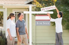 Real estate agent hanging sign outside house