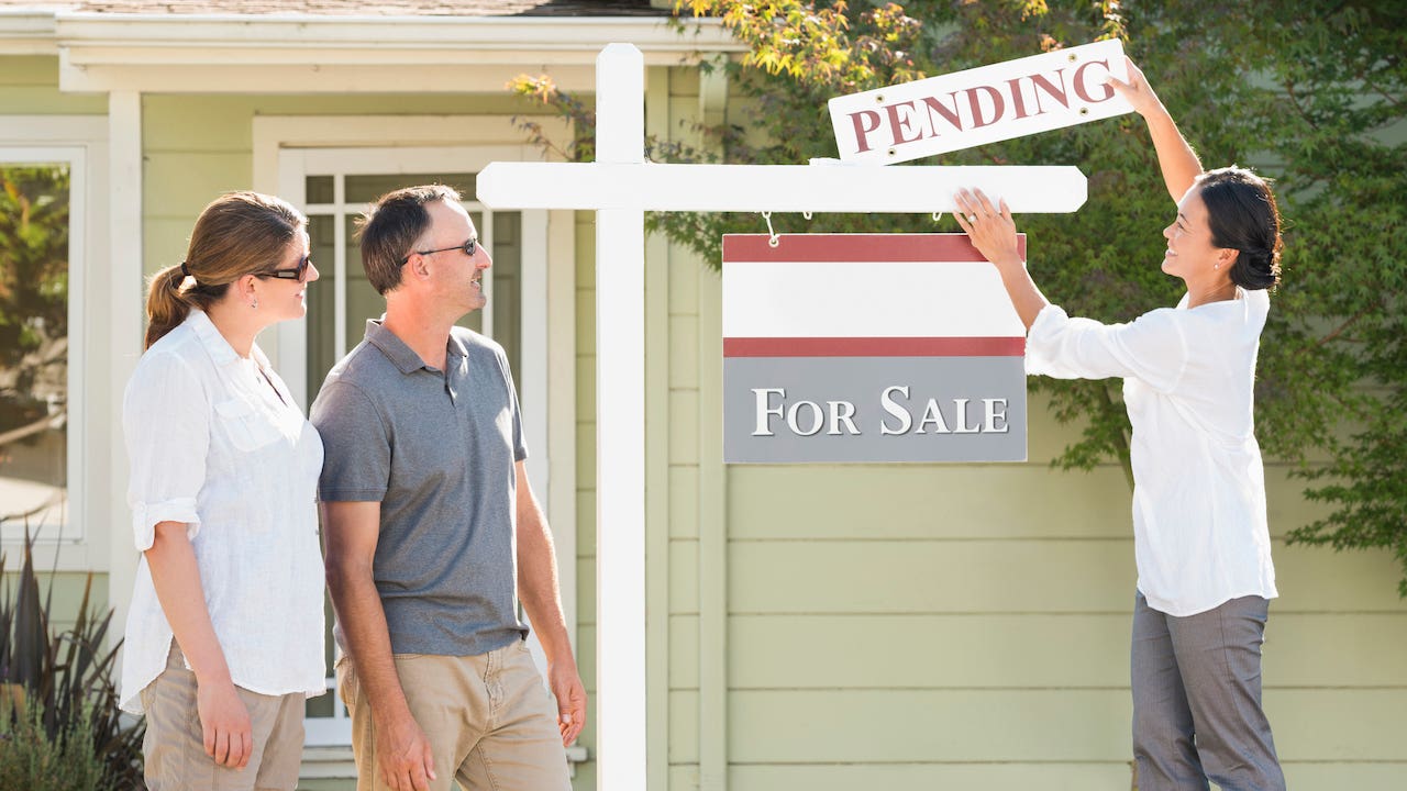 Real estate agent hanging sign outside house