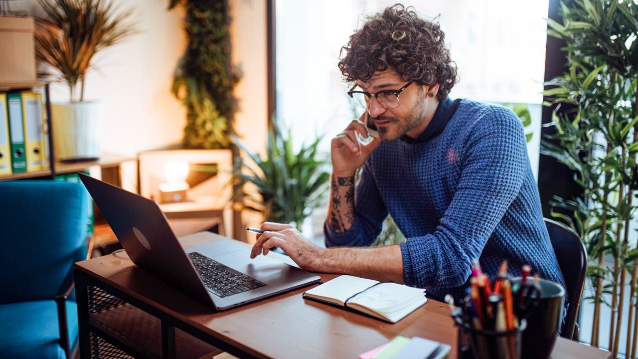 man talking on the phone while working on his computer