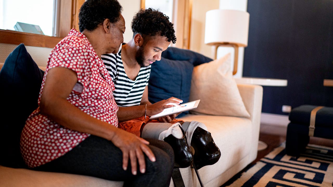 grandson using a digital tablet with his grandmother