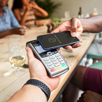 person paying for a bill at a restaurant with contactless phone app