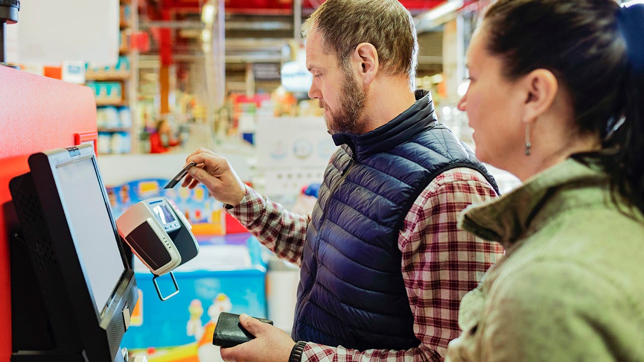 Man paying with credit card while shopping with woman at supermarket