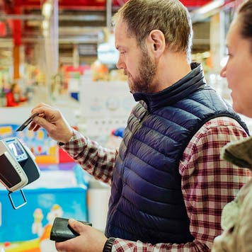 Man paying with credit card while shopping with woman at supermarket