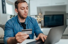 man holding credit card and shopping online at home