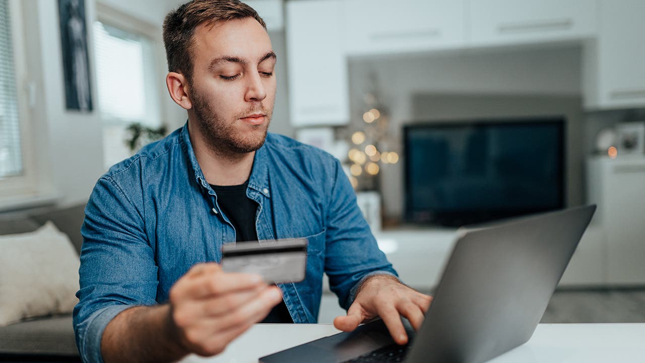man holding credit card and shopping online at home