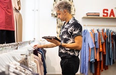 clothing store owner taking inventory on a digital tablet
