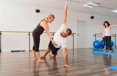Fitness instructor teaching posture to man exercising in pilates class