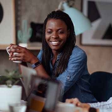 Woman holds a cup of coffee and looks at a computer