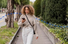 woman looking at her phone while on a walk