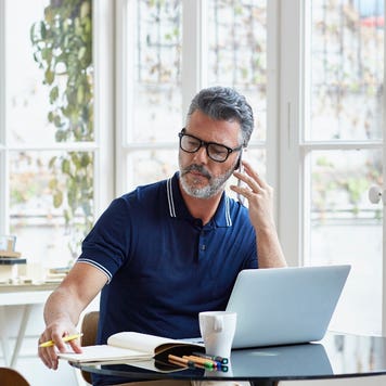 Man talks on the phone while working at a laptop