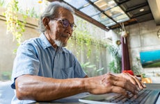 Older gentleman using laptop in living room