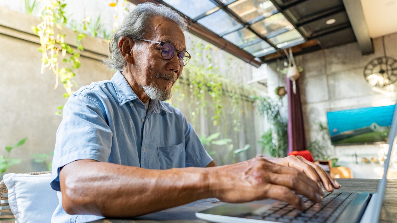 Older gentleman using laptop in living room