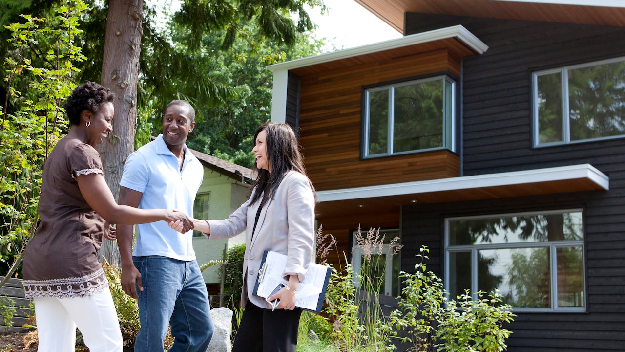 Real estate agent greeting couple at house