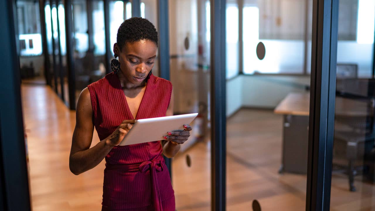 businesswoman walking in an office and looking at a digital tablet