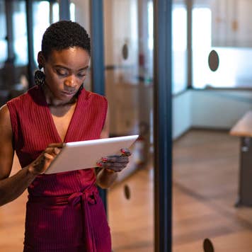businesswoman walking in an office and looking at a digital tablet