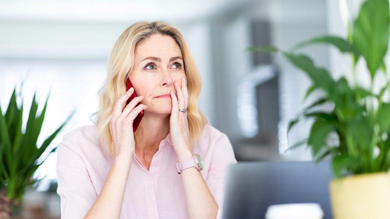 Woman talking on smart phone at home office