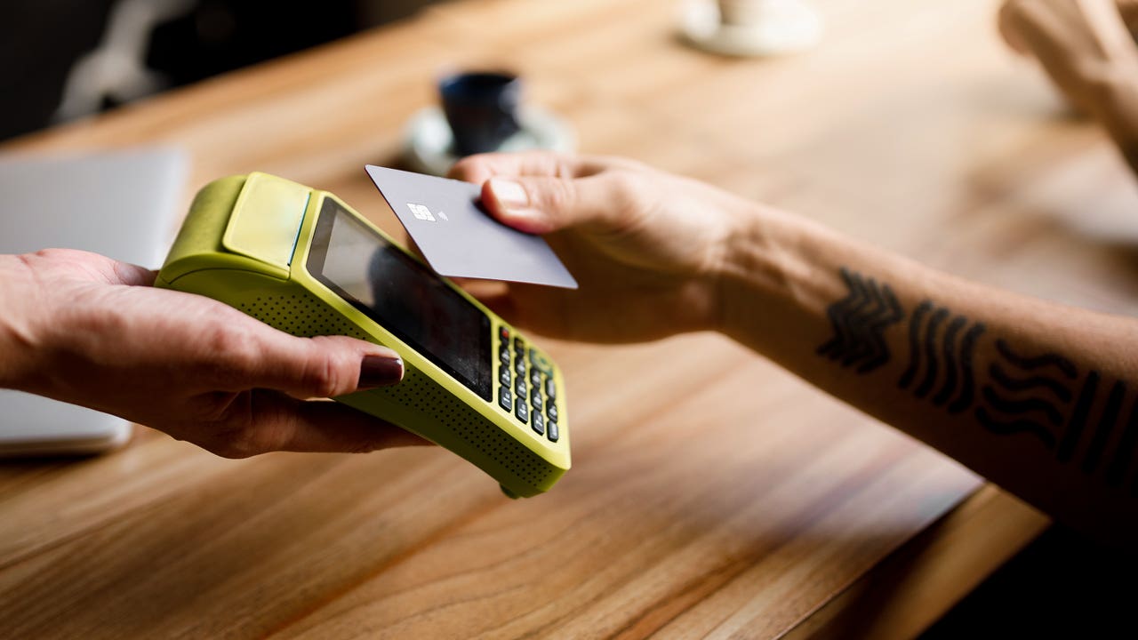 hand paying with credit card at contactless reader