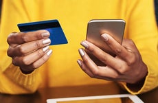 close up of a woman holding a smartphone and a credit card