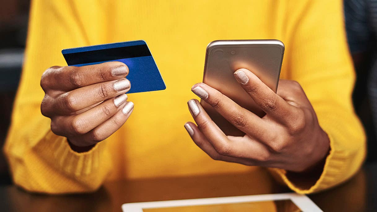close up of a woman holding a smartphone and a credit card