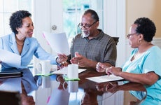 What is a flat fee - older african american couple going over paperwork with a smiling african american real estate agent at the kitchen table