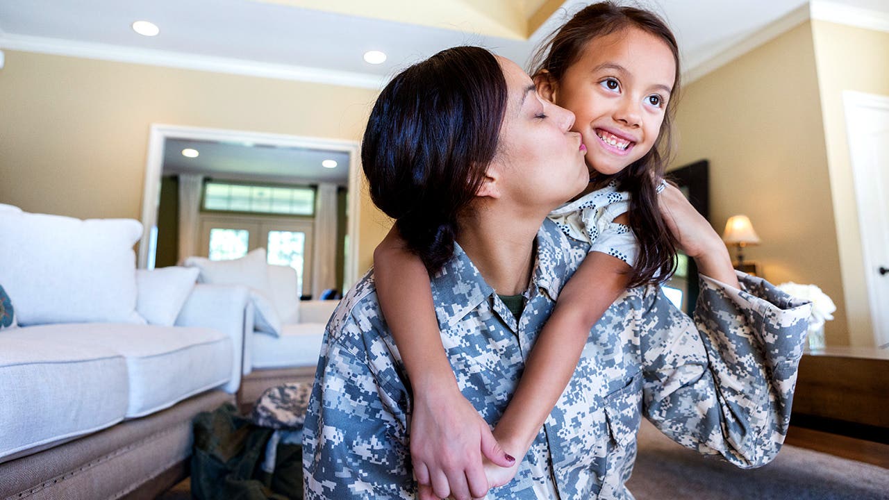 mom in uniform kisses daughter at home