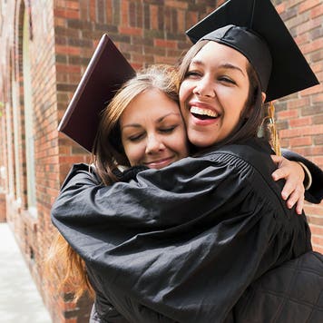 mother hugs daughter wearing a graduation hat