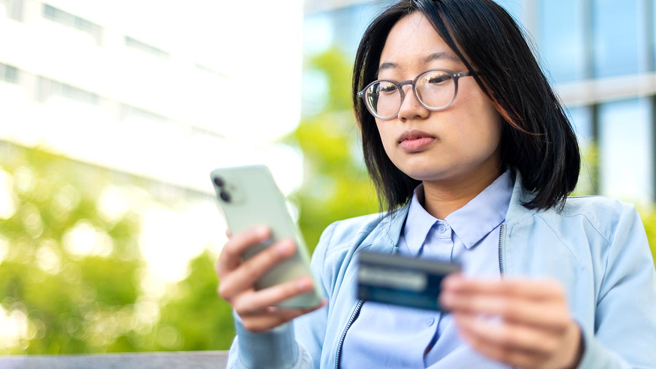 young woman looking at a phone and credit card