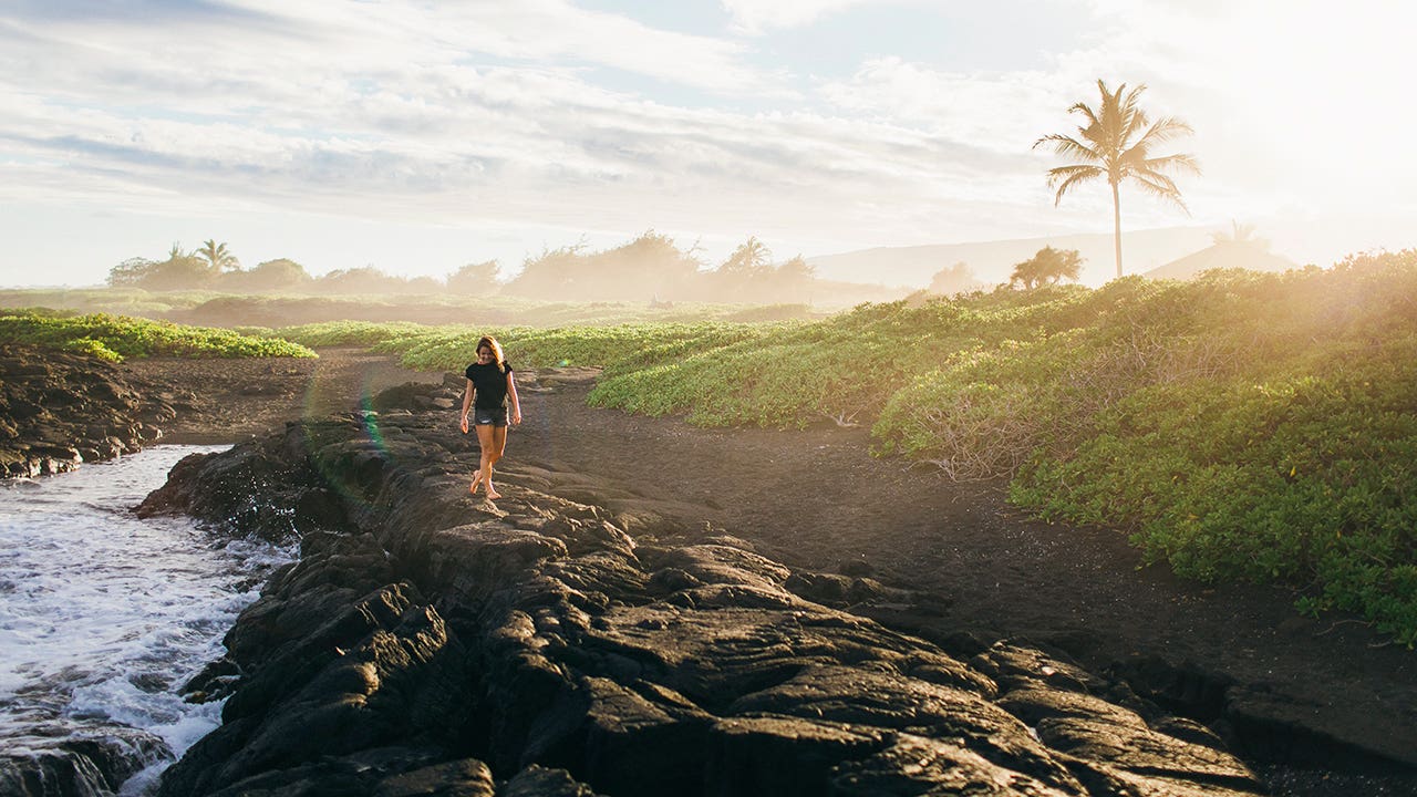 a girl walking on the coast in hawaii