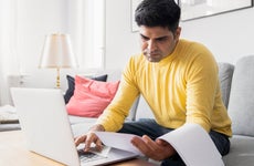 man reviewing paperwork while paying bills online