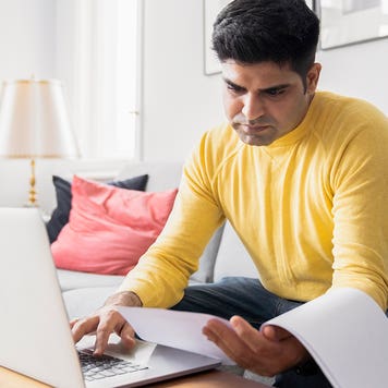 man reviewing paperwork while paying bills online