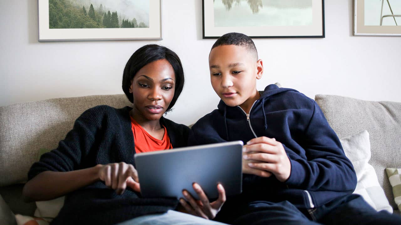 mother and son looking at digital tablet together in the living room