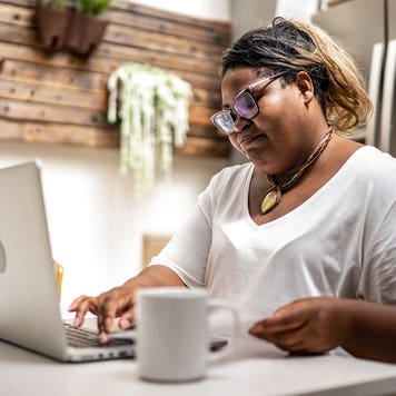 person working on laptop at the kitchen table