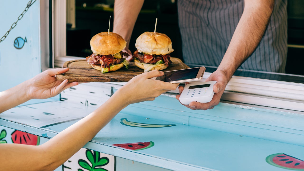 close up of hands using mobile payment for burgers from a food truck