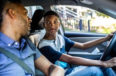 teenage son driving with his father