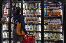 A woman looks in the dairy section of a grocery store