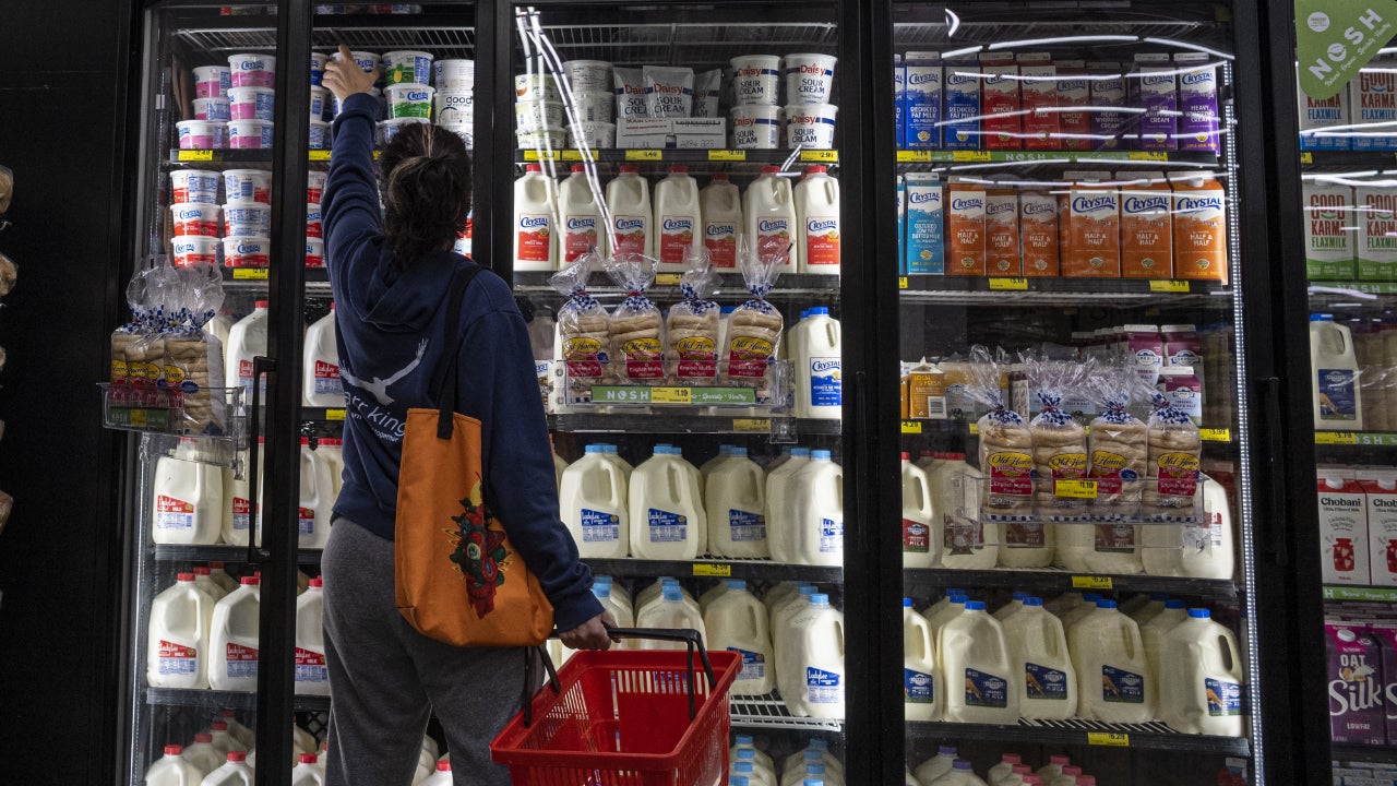 A woman looks in the dairy section of a grocery store