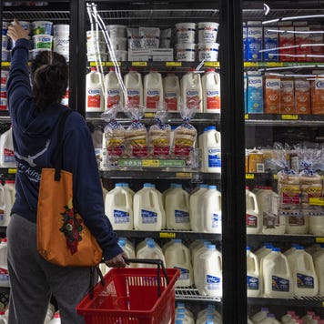 A woman looks in the dairy section of a grocery store