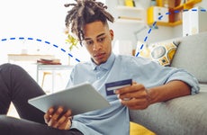 man looking at credit card and digital tablet