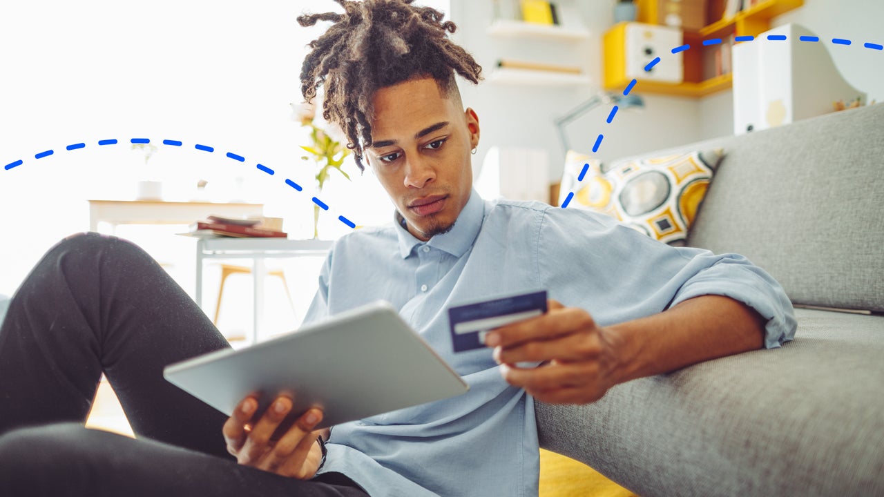 man looking at credit card and digital tablet