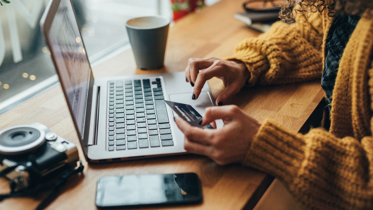 close up of person holding a credit card and typing on a computer